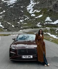 a woman standing next to a brown car