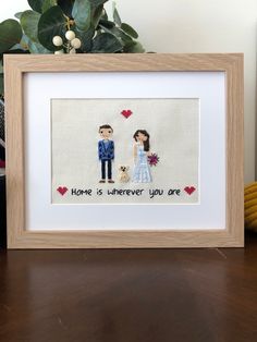 a cross - stitch picture frame with a couple holding hands and the words home is wherever you are