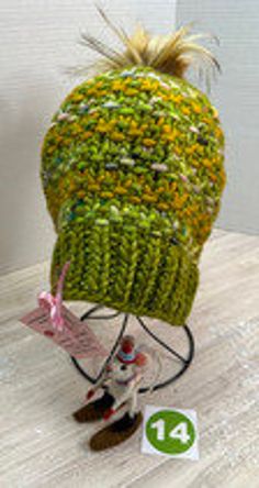 One-of-a-kind, ready-to-ship, handmade winter hat/beanie.  Bursting with color, this green, and mustard yellow multi-colored beanie features a 4" gold, faux fur, removable PomPom.  Made of fine Malabrigo Rasta wool yarn, this beanie must be hand washed and dried flat to preserve its softness and durability.  The hat measures 8" across and 9" tall allowing the wearer to pull it down over the ears or roll it up depending on the required warmth.  Knit from my own original design, The Poppy Hat pattern is available on Ravelry for the adventurous beginning knitter.  As with any handmade item, minor flaws and imperfections are inherent to its construction and adds a unique charm to the finished project. Yellow One Size Fits Most Beanie, Green Winter Hat For Cold Weather, Green Winter Beanie Cap, Multicolor One-size Beanie For Outdoor, Green Beanie Cap For Winter, Multicolor One Size Beanie For Outdoor, Adjustable Yellow Winter Beanie, Green Winter Bonnet (one Size Fits Most), Green Winter Bonnet, One Size