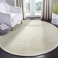 a living room with a white chair and rug on the floor in front of a window