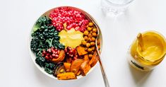 a bowl filled with different types of food next to a glass of orange juice and a spoon