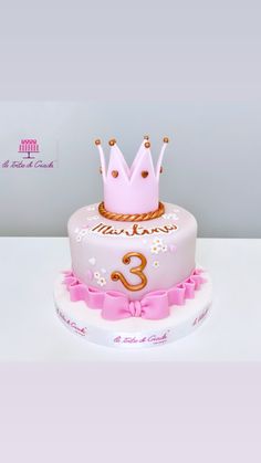 a pink birthday cake with a crown on top and the number 3 in gold lettering