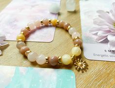 This bracelet is handcrafted and Reiki Infused from natural 8mm Yellow Calcite, Peach Moonstone and Morganite beads. Complete with gold accents and a gold daisy charm in the center. Yellow Calcite is a wonderful crystal for helping you through persistent issues by getting your energy moving and encouraging you to take a new look at accomplishing your goals. It can be used for healing emotional issues related to shame, shyness, and social phobias. Yellow Calcite can also be used to move energy th Crystal Uses, Spring Bracelet, Yellow Calcite, Daisy Charm, Healing Therapy, Moonstone Crystal, Sacral Chakra, Peach Moonstone, Sound Healing