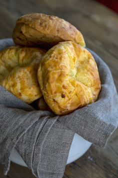 three pieces of bread sitting on top of a cloth covered plate in front of a wooden table