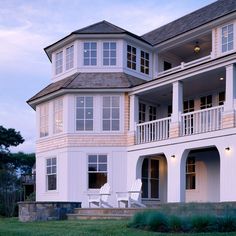 a large white house sitting on top of a lush green field