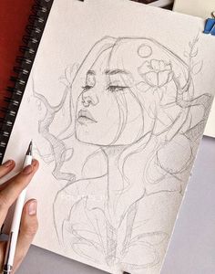 a drawing of a woman's face is being drawn on paper with a marker