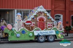 a truck decorated with gingerbread houses and decorations on the back is parked in front of a building