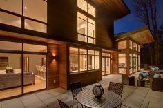 an outdoor patio with table, chairs and couches at night in front of the house