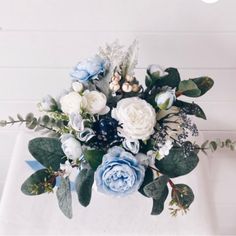 a bouquet of flowers sitting on top of a white cloth covered table with greenery