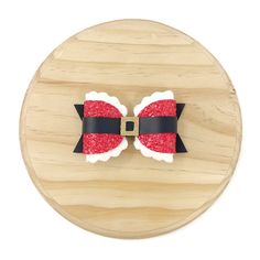 a wooden board with a red and black bow on it's side, cut out to look like santa claus