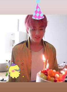 a person with pink hair and a birthday hat holding a cake with candles in it