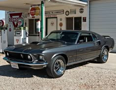 an old mustang parked in front of a gas station