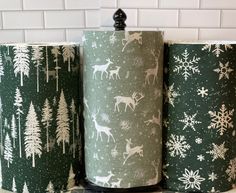 three rolls of toilet paper with deer and snowflakes on them sitting on a counter