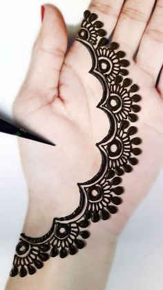 a woman's hand with henna on it and a pen in the other hand