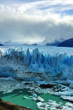 an iceberg in the water with mountains in the background