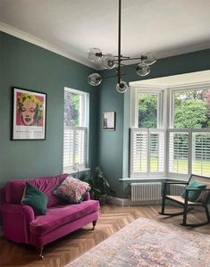 a living room filled with furniture and windows covered in shades of green, pink and purple