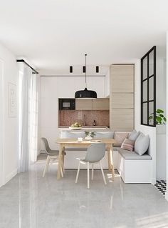 a white kitchen and dining room with an l shaped table in the center surrounded by gray chairs