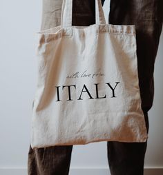 a person holding a tote bag with the word italy printed on it