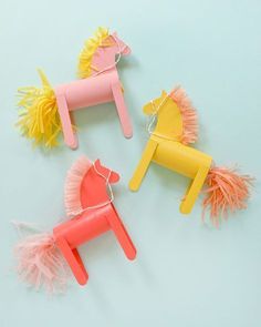 three plastic toy horses with pom poms attached to them on a blue background