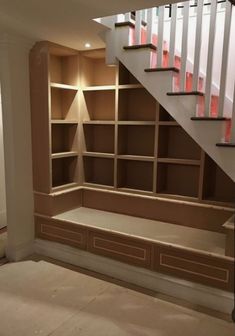 an empty room with some shelves under the stairs and a light fixture on the wall