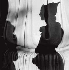 a black and white photo of a person's shadow on the back of a bench