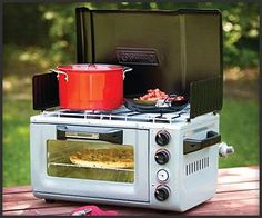 an oven sitting on top of a picnic table with pots and pans in it