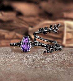 a purple stone ring sitting on top of a table next to a leafy plant