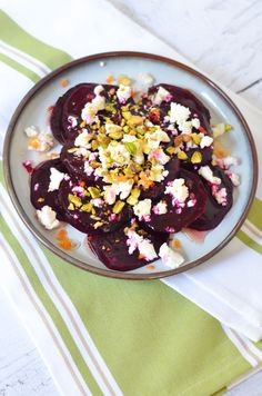 beets and white cheese on a plate with a green striped table cloth next to it