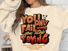 This motivational hoodie features the bold statement "You Only Fail When You Stop Trying" in vibrant orange and yellow hues. Available on Hoodies Gildan 18500, Sweatshirts Gildan 18000, and Long Sleeve T-Shirts Gildan 2400, this unisex design is perfect for daily inspiration. The design encourages perseverance and determination, making it a great gift for anyone in need of a motivational boost. Pair it with your favorite jeans or sweatpants for a casual look that spreads positivity. *GILDAN 1850 Relaxed Fit Slogan Hoodie, Relaxed Fit Hoodie With Slogan, Inspirational Slogan Sweatshirt For Streetwear, Inspirational Streetwear Tops For Fall, Inspirational Graphic Print Hoodie For Streetwear, Motivational Hoodies, Message Positif, Yellow Hues, Stop Trying