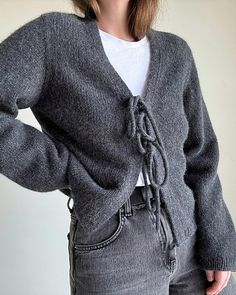 a woman is wearing a gray sweater and jeans