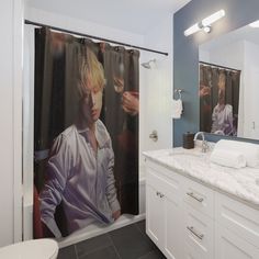 a bathroom with a shower curtain that has a photo of a man on it in the mirror