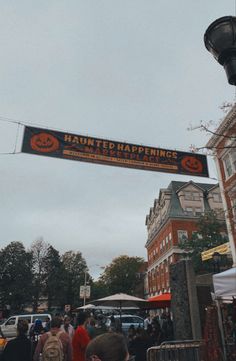 there is a sign that says happy halloween hanging from the side of a street light