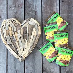 a heart shaped bowl filled with bananas next to five bars of banana snack wrappers