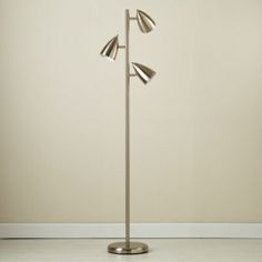 a floor lamp with three lights on it in an empty room next to a wall