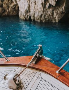 the steering wheel on a sailboat with blue water and cliffs in the background