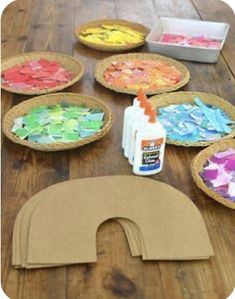 paper plates are arranged on a wooden table with paint and craft supplies in the middle