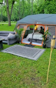 a tent set up in the middle of a grassy area with furniture and decorations around it