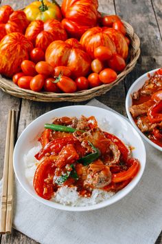 two bowls filled with meat and vegetables on top of white rice next to baskets of tomatoes