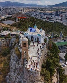 an aerial view of a white building on top of a hill with people walking around it