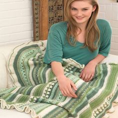 a woman sitting on a couch with a green and white blanket