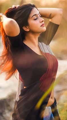 a woman with red hair is posing for the camera and has her arms behind her head