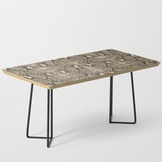 a wooden table with black metal legs and a patterned design on the top, against a white background