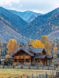 a large log house sitting in the middle of a lush green field surrounded by mountains