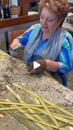 a woman sitting at a table cutting bamboo stalks