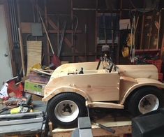 an unfinished car is being worked on in a garage with tools and woodworking equipment