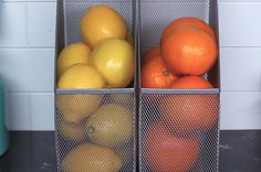 two metal containers filled with oranges and lemons