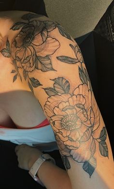 a woman's arm with flowers and leaves tattooed on the side of her body