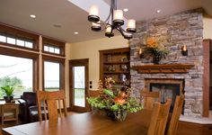 a dining room table with chairs and a fireplace in the background, surrounded by windows