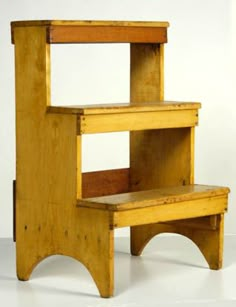 a wooden step stool sitting on top of a white floor