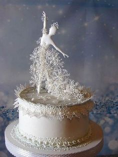 a white cake topped with frosting and a ballerina figure